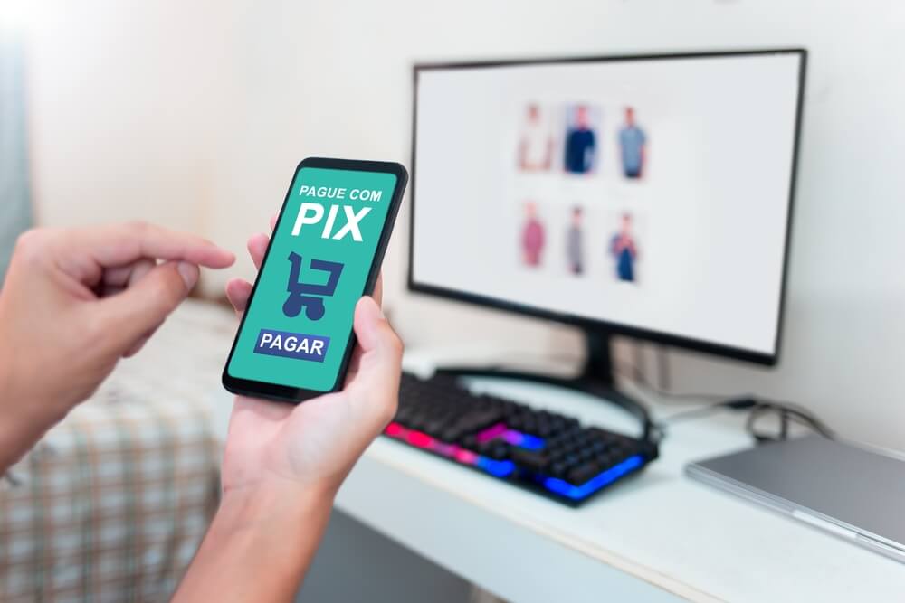 Uma pessoa está segurando um celular e utilizando-o para realizar um pagamento via pix