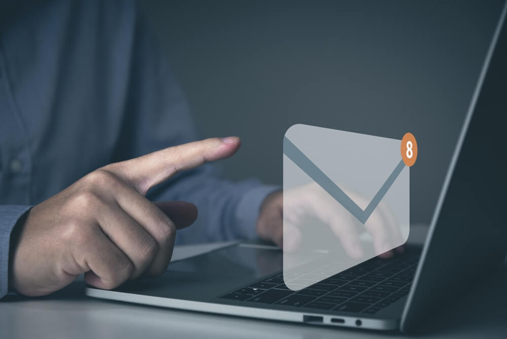 Notebook com o desenho de um envelope de carta representando o e-mail. Um homem está clicando nela.