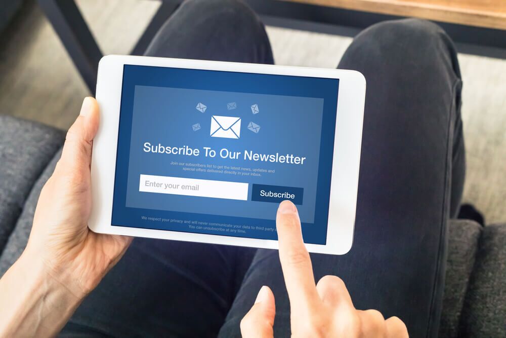 Imagem de uma pessoa utilizando um tablet e se inscrevendo em uma newsletter.
