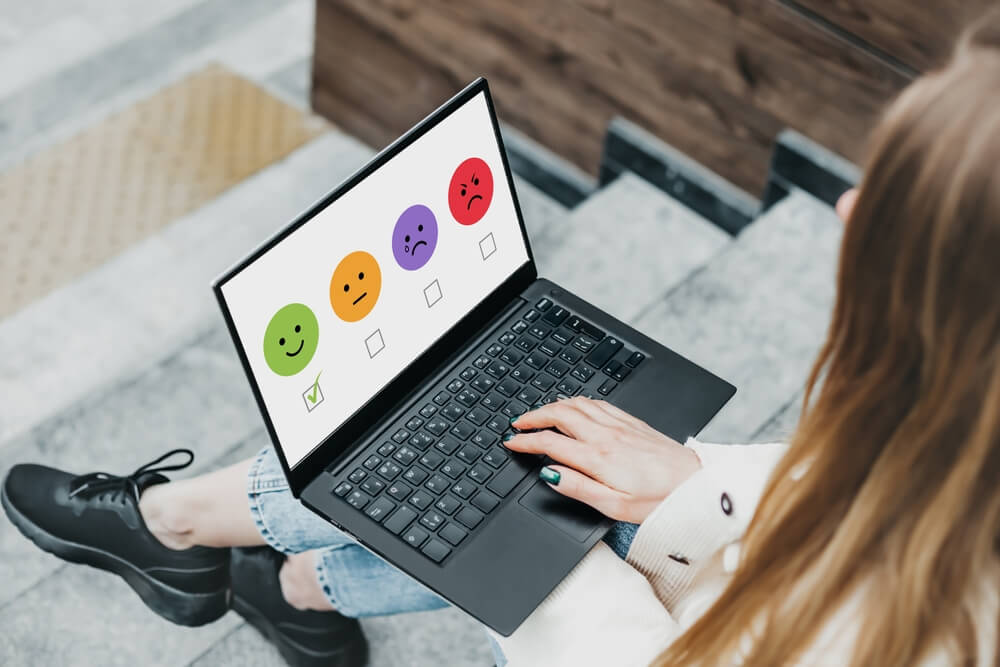 Ua mulher está respondendo a uma pesquisa de satisfação ao consumidor no computador.