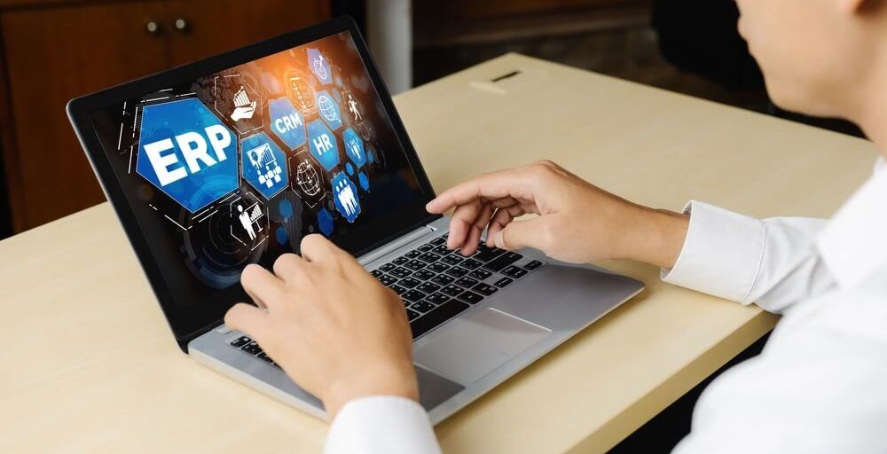 Imagem De Uma Pessoa Utilizando Um Computador. Na Tela Do Notebook Está Escrito "ERP".