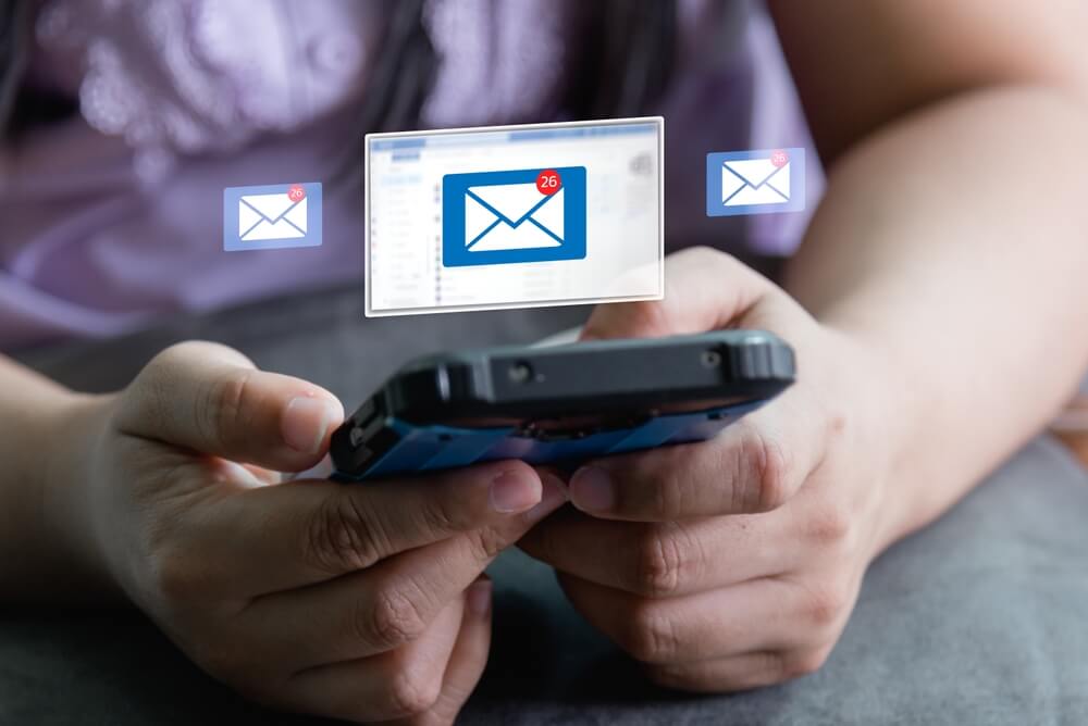Imagem de uma pessoa utilizando o celular. Ela está recebendo e-mails marketings.