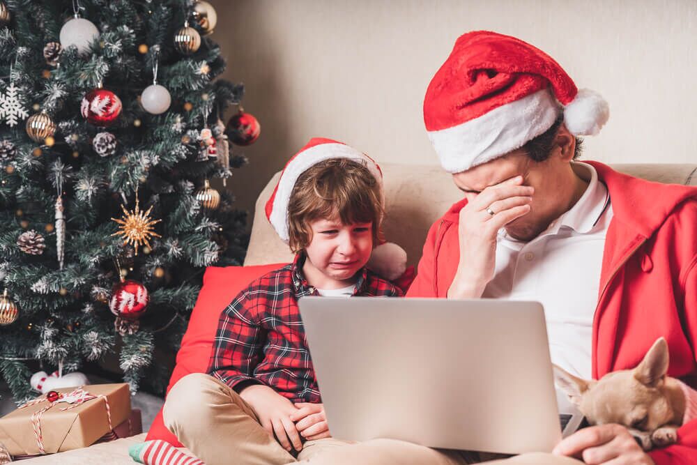 Imagem de uma criança e de um pai em época de Natal. Eles estão emocionados na frente do computador.